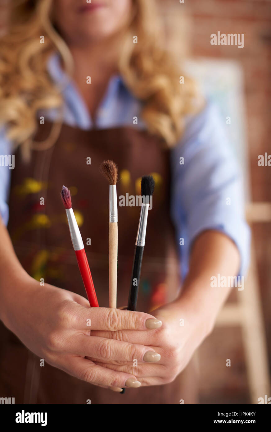 Close up of human hands holding paintbrushes Banque D'Images