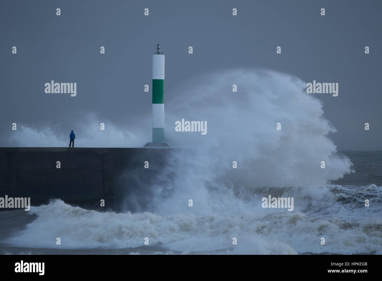 Risquer un homme debout sur une jetée que les grosses vagues crash sur lui pendant les Doris Banque D'Images