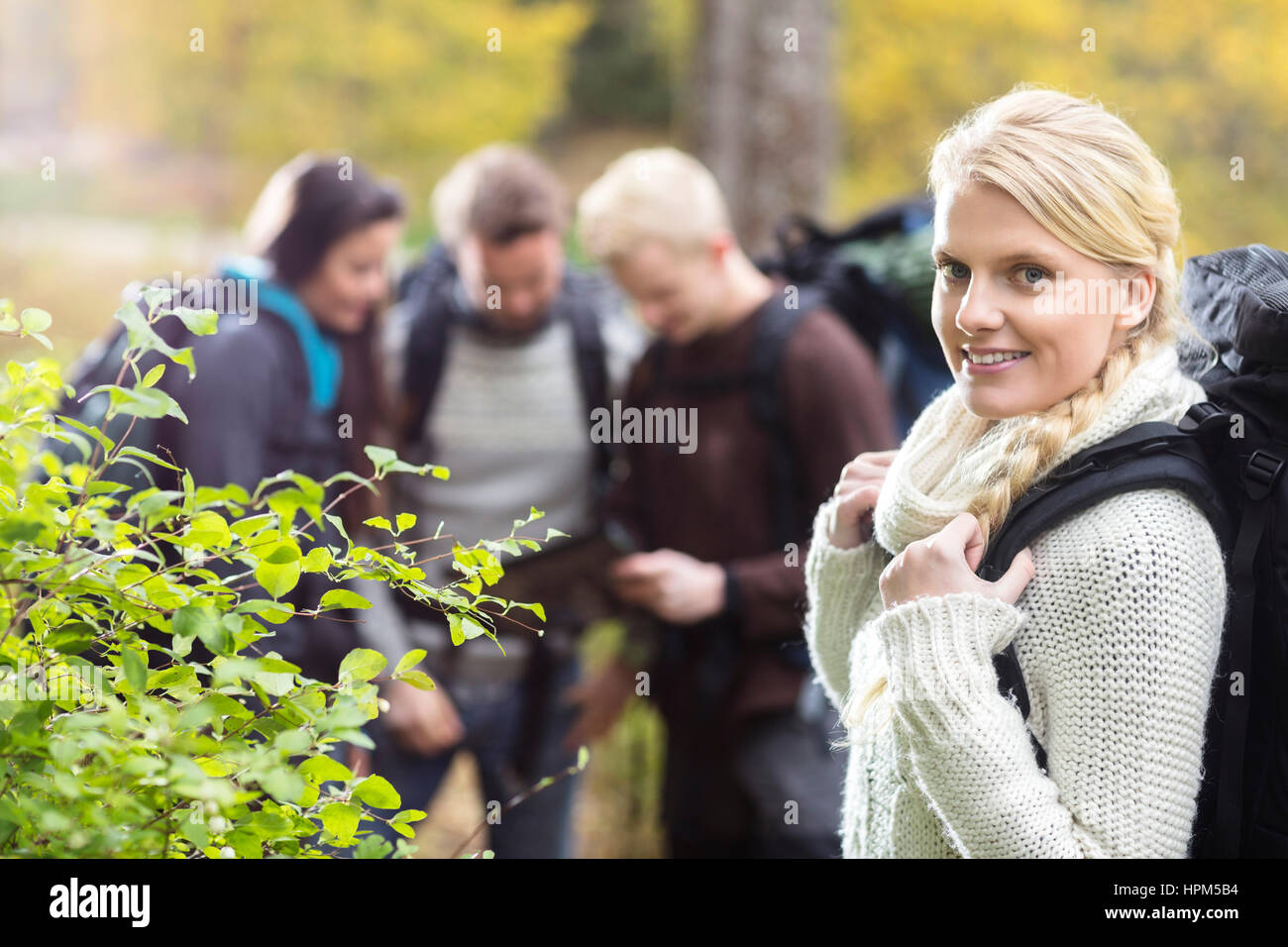 Portrait of smiling young woman randonneur avec des amis à discuter en arrière-plan de Forest Banque D'Images