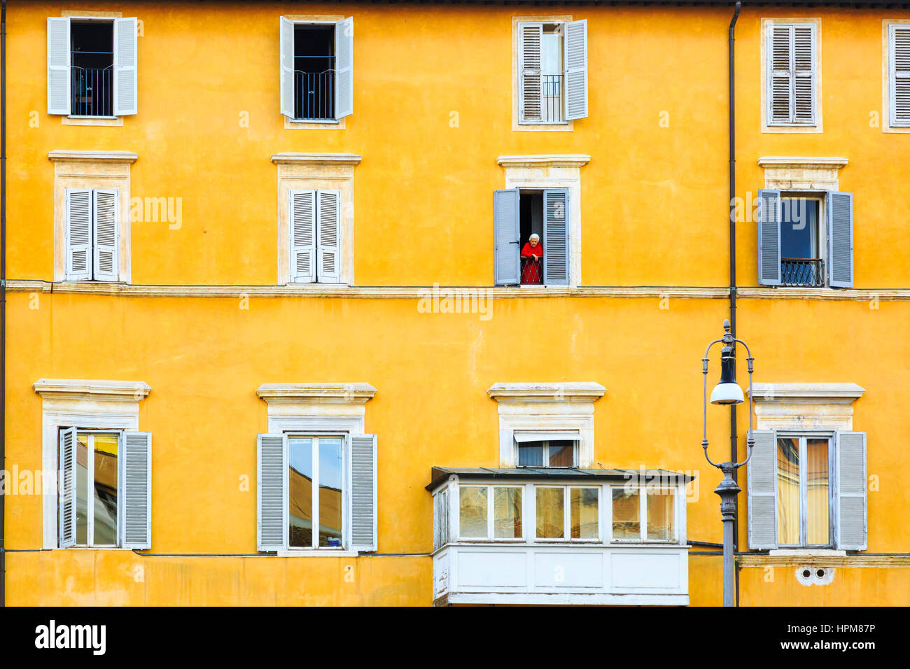 Vieille Femme portant une robe rouge l'article sur le balcon de son appartement à Rome, Italie Banque D'Images