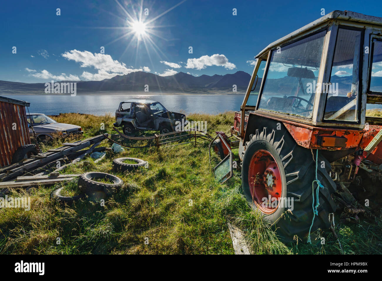 Old farm equipment, pneus de jeep et sur les terres agricoles, Faskrudsfjordur, Islande Banque D'Images