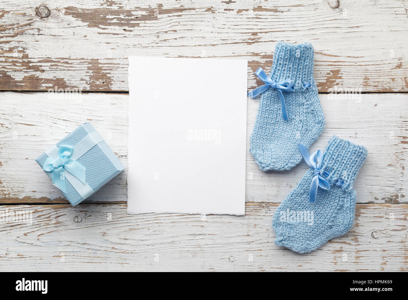 Beau cadeau, chaussettes du bébé et carte postale vierge sur fond de bois blanc. Mise à plat Banque D'Images