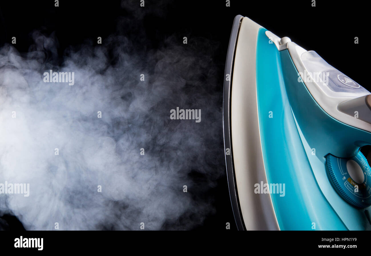 Fer à repasser dans la main et la vapeur blanche sur fond noir Banque D'Images