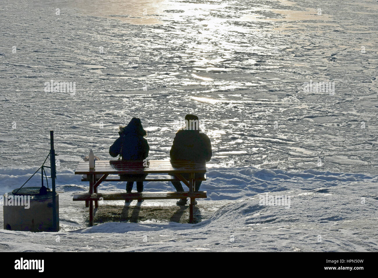 Deux personnes assises sur un banc en face de la mer gelée. Banque D'Images