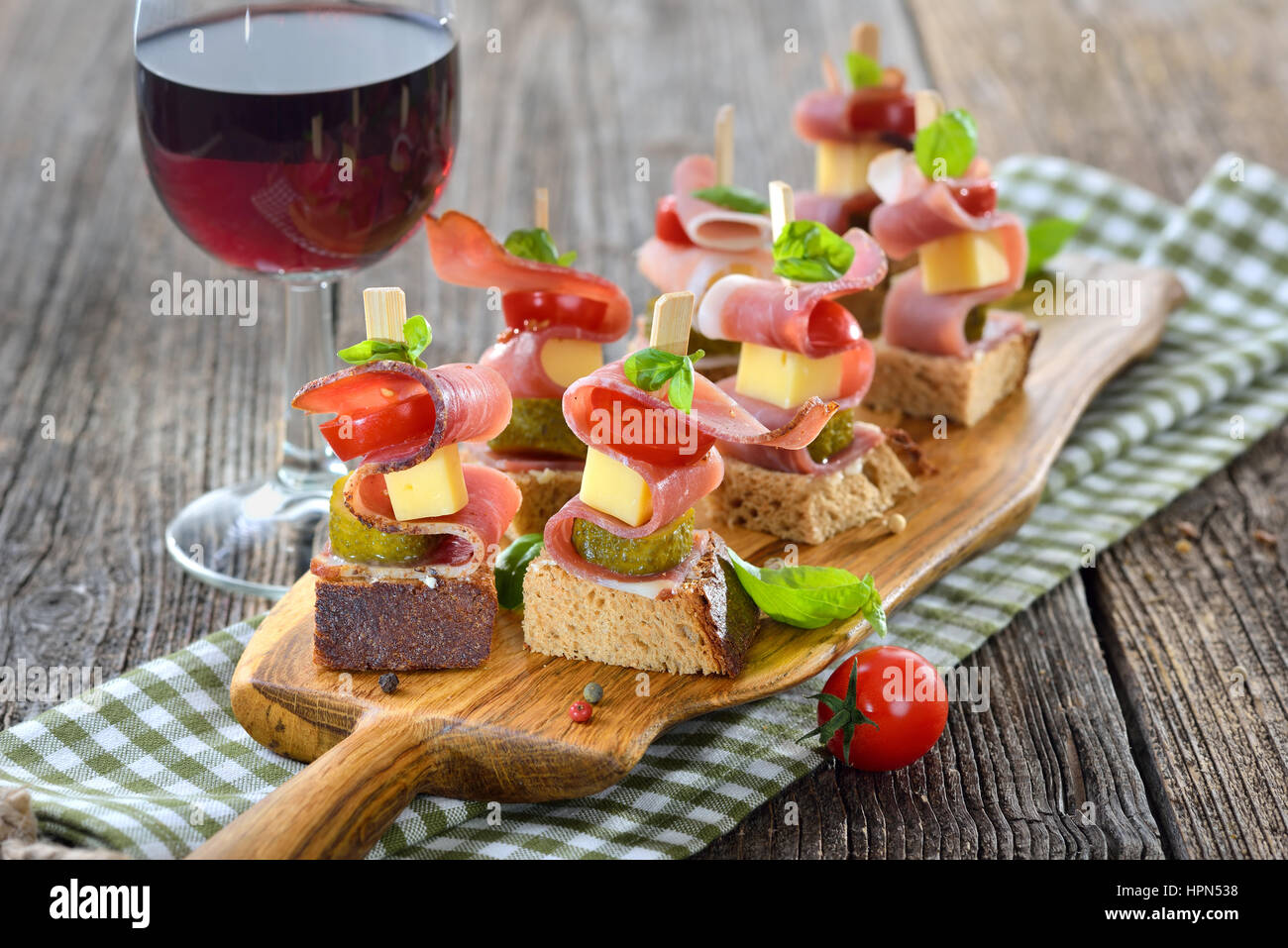 Apéritifs du Tyrol du Sud : pain de campagne frais beurré avec le lard fumé, fromage de montagne copieux, les cornichons et les tomates, les feuilles de basilic sur le dessus Banque D'Images Apéritifs du Tyrol du Sud : pain de campagne frais beurré avec le lard fumé, fromage de montagne copieux, les cornichons et les tomates, les feuilles de basilic sur le dessus Banque D'Images