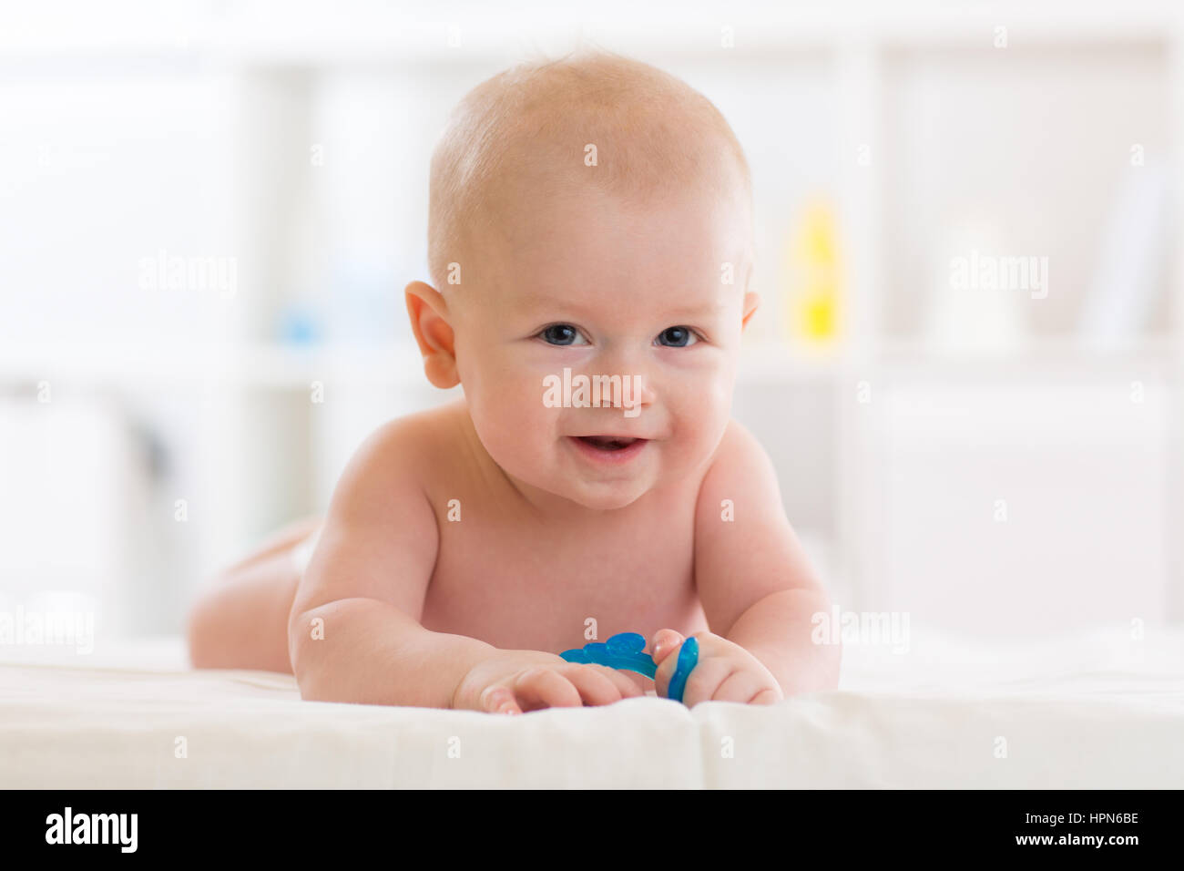 Bébé garçon couché sur le ventre dans la chambre à coucher de soleil blanc. Le nouveau-né de l'relaxing in bed Banque D'Images