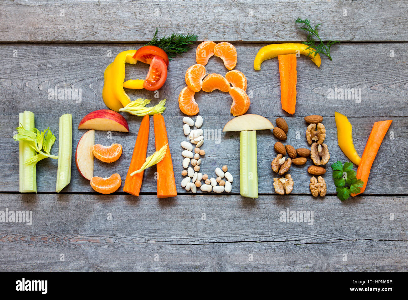 Mots "Manger sain" écrit avec légumes, fruits, noix et légumineuses sur fond de bois rustique, concept - ingrédients biologiques pour mourir végétalien sain Banque D'Images