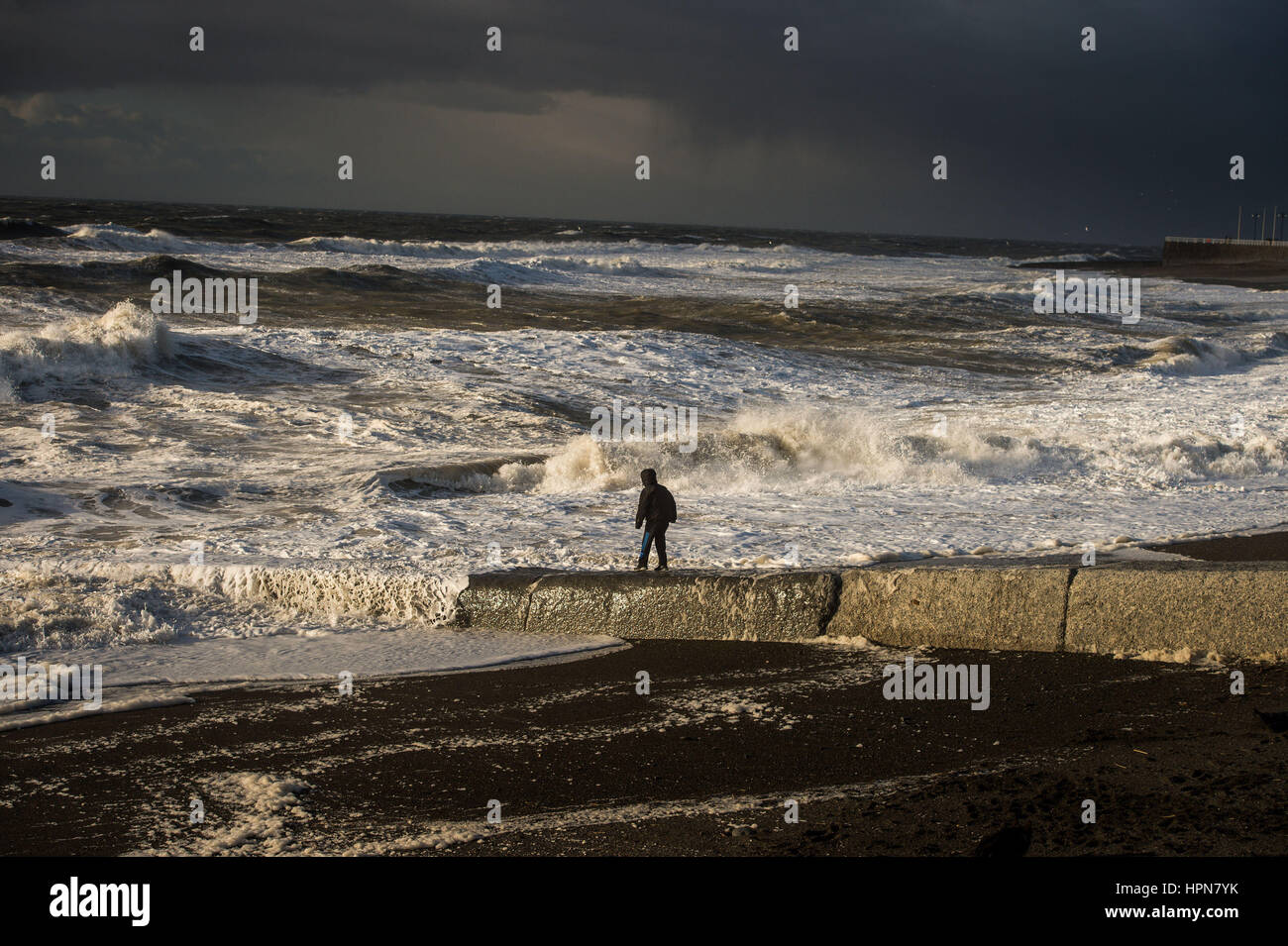 Un garçon joue sur la plage sur un fond de mer difficile à Aberystwyth, Pays de Galles, que les vols ont été annulés et les banlieusards ont été avertis qu'ils connu des retards après la tempête Doris atteint près de 90mph sur sa façon de battre la Grande-Bretagne. Banque D'Images