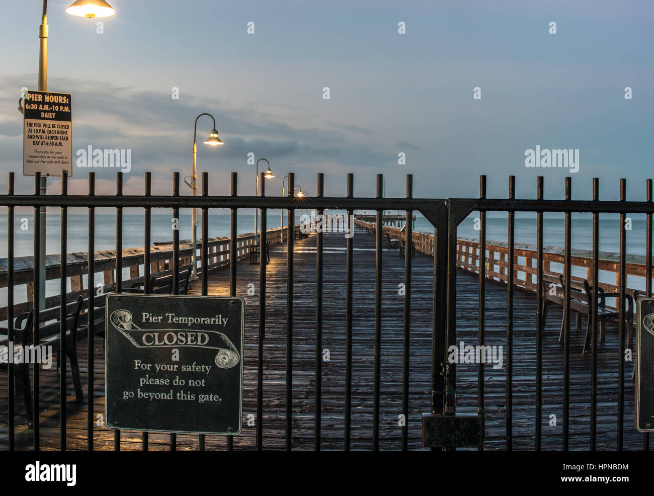 Vue panoramique de lampes glow le long de jetée de Ventura derrière des grilles verrouillées à l'aube. Banque D'Images