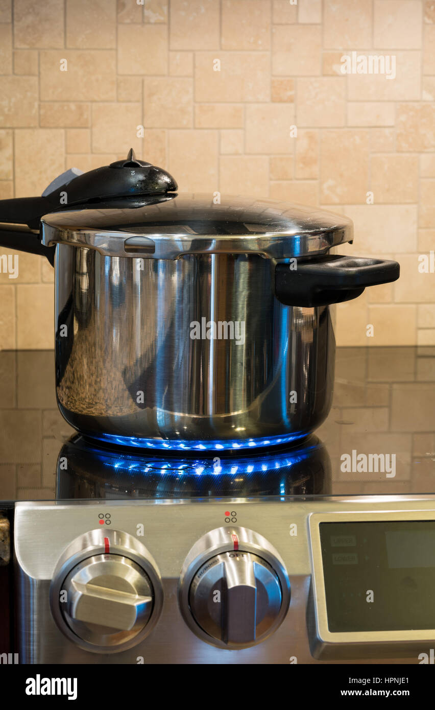 Acier inoxydable autocuiseur se défouler sur une plaque de cuisson à induction modernes avec plateau en verre Banque D'Images