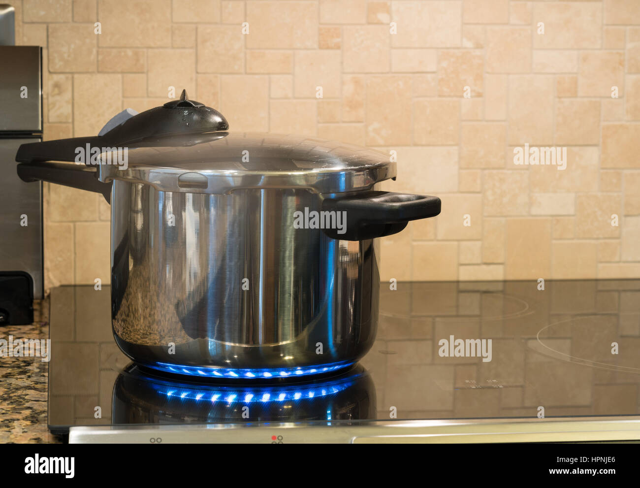 Acier inoxydable autocuiseur se défouler sur une plaque de cuisson à induction modernes avec plateau en verre Banque D'Images