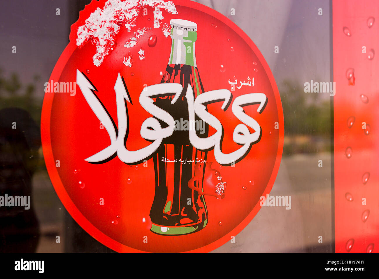 AL AIN, ÉMIRATS ARABES UNIS - Rouge Coca-cola inscription en arabe, montrant une bouteille de coke. Banque D'Images