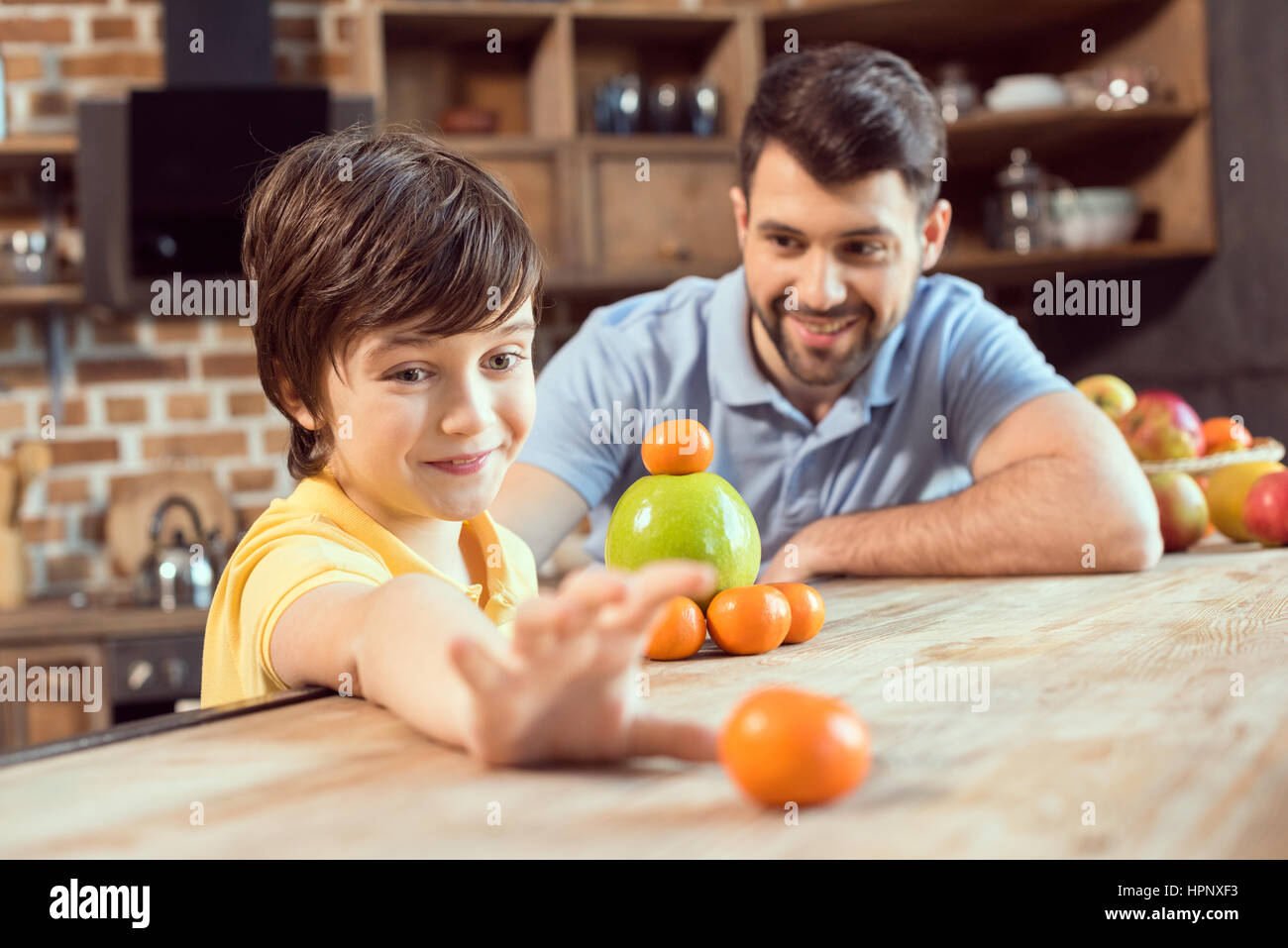 Père et fils jouant avec les agrumes dans la cuisine Banque D'Images