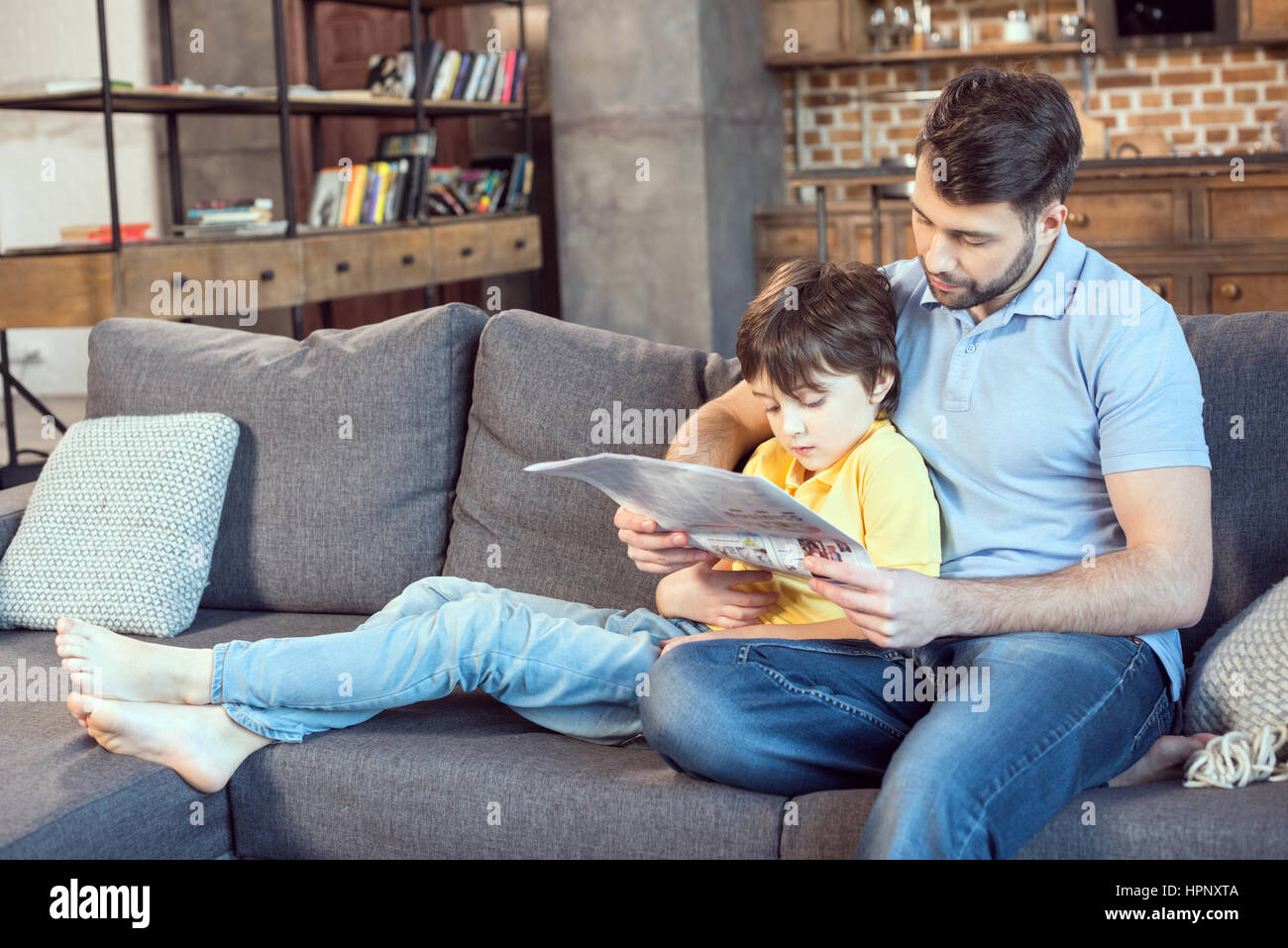 Le père et le fils ensemble à la maison de journal de lecture Banque D'Images