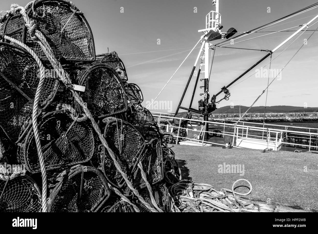 Pile de casiers de pêche amarrés contre Bateau de pêche dans le port Banque D'Images
