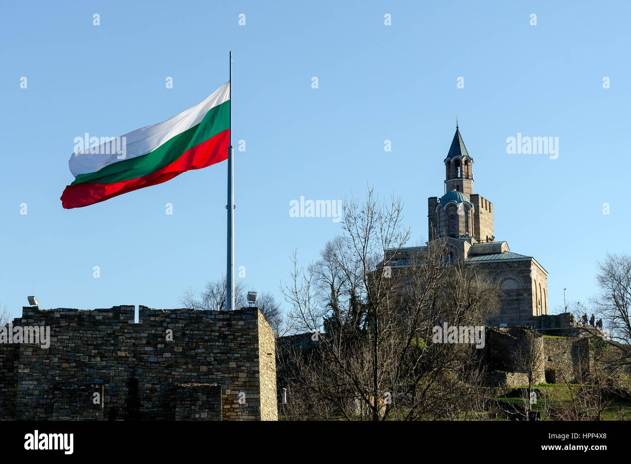 En agitant le drapeau bulgare forteresse Tsarevets avec le patriarche en arrière-plan, Veliko Tarnovo, Bulgarie Banque D'Images