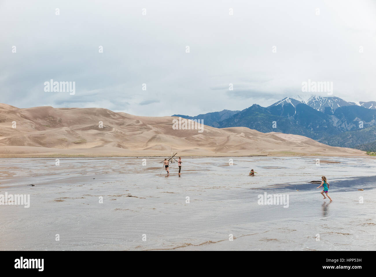 Personnes traversant un ruisseau / de l'eau pour obtenir des dunes au Great Sand Dunes National Park and Preserve, Colorado Banque D'Images