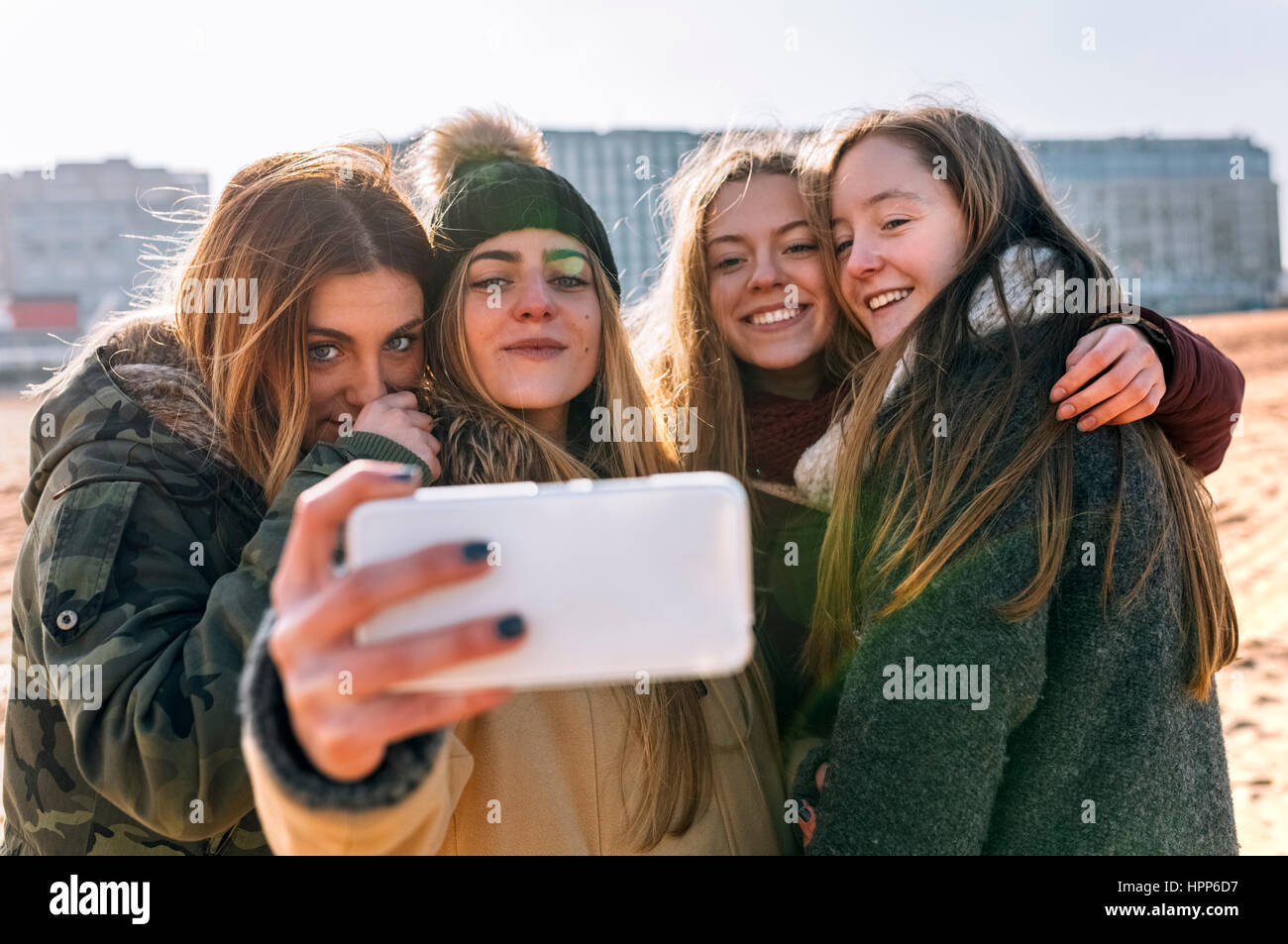 Quatre amis en tenant avec selfies téléphone cellulaire sur la plage Banque D'Images