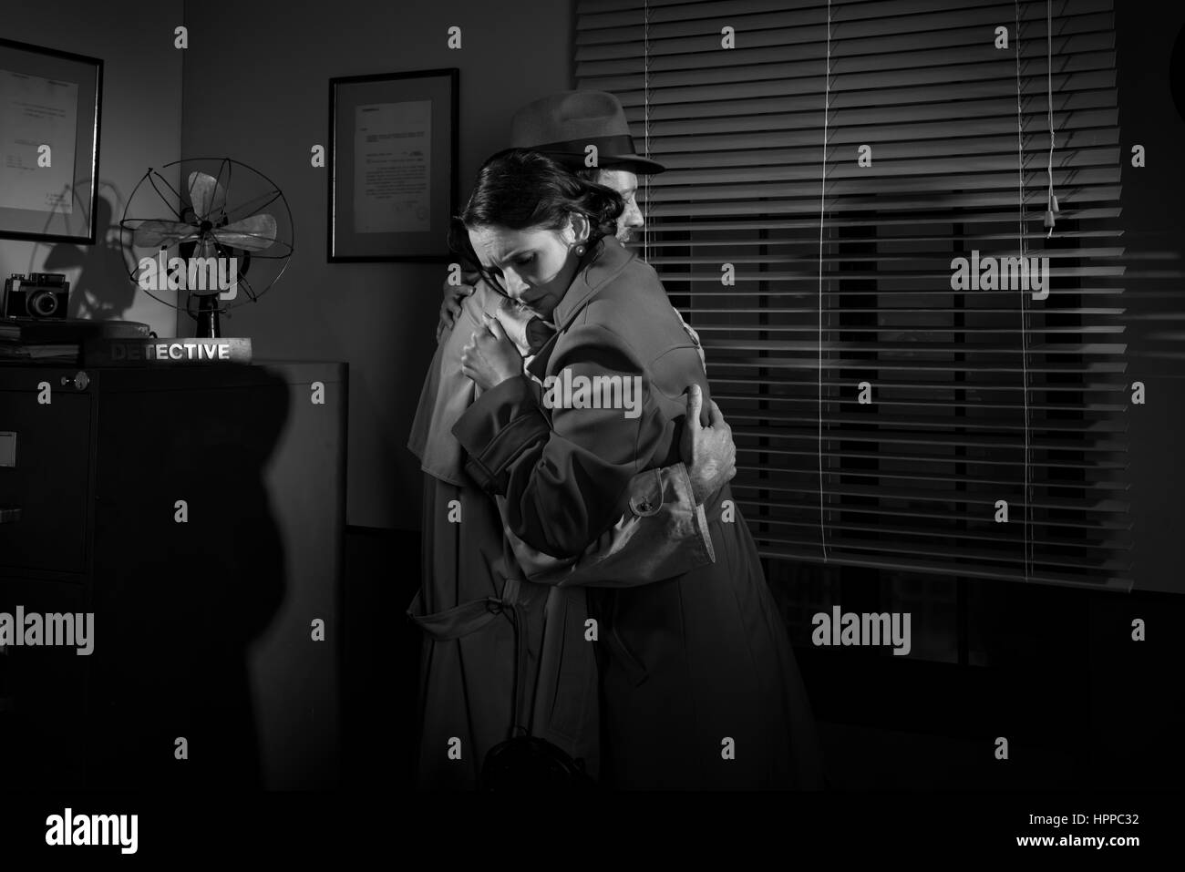 Consolante détective et serrant une jeune femme dans son bureau, scène du film noir. Banque D'Images