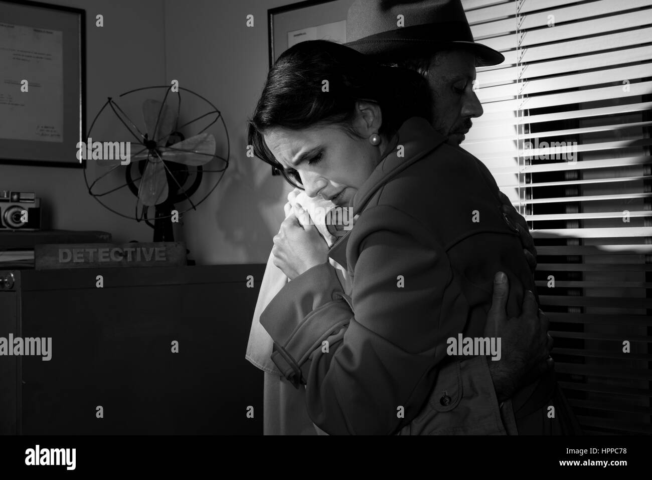 Consolante détective et serrant une jeune femme dans son bureau, scène du film noir. Banque D'Images