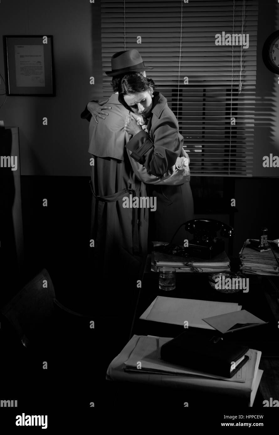 Consolante détective et serrant une jeune femme dans son bureau, scène du film noir. Banque D'Images