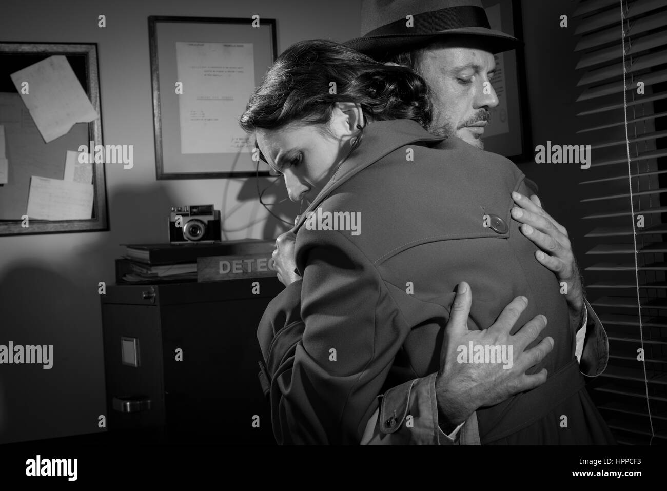Consolante détective et serrant une jeune femme dans son bureau, scène du film noir. Banque D'Images