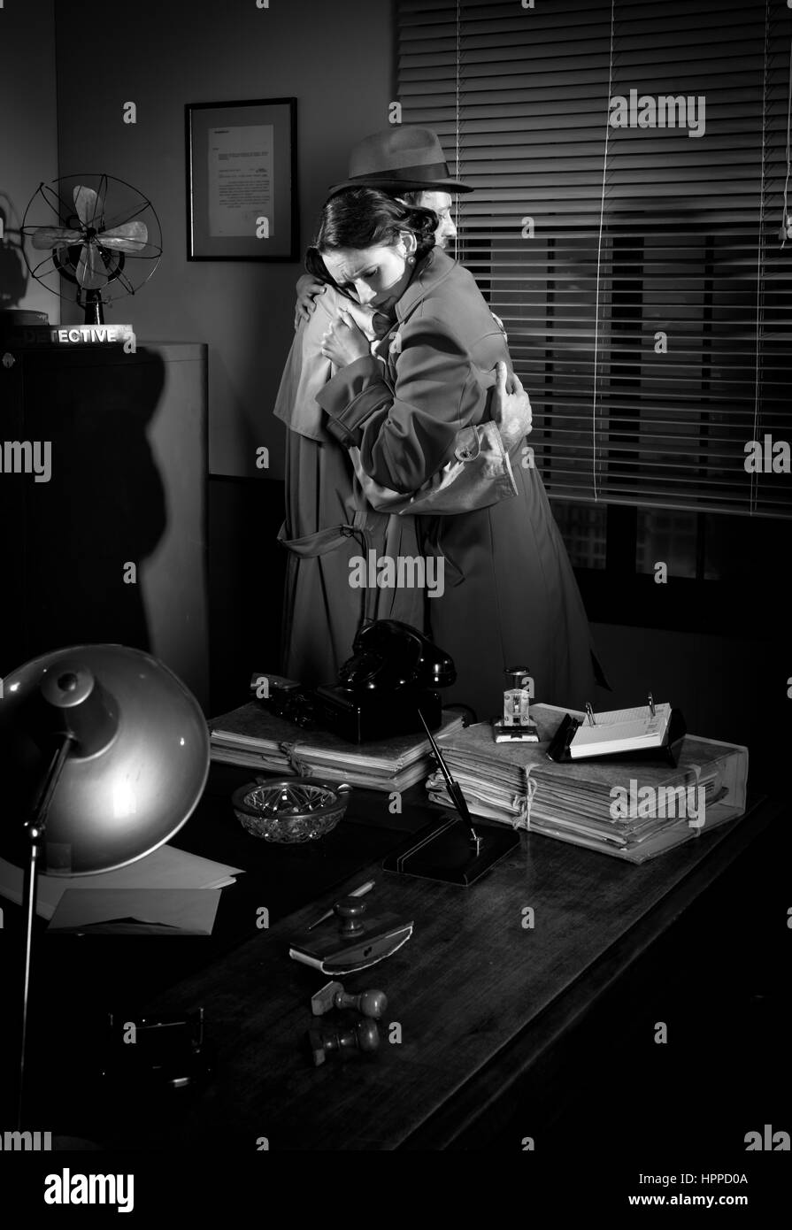 Consolante détective et serrant une jeune femme dans son bureau, scène du film noir. Banque D'Images