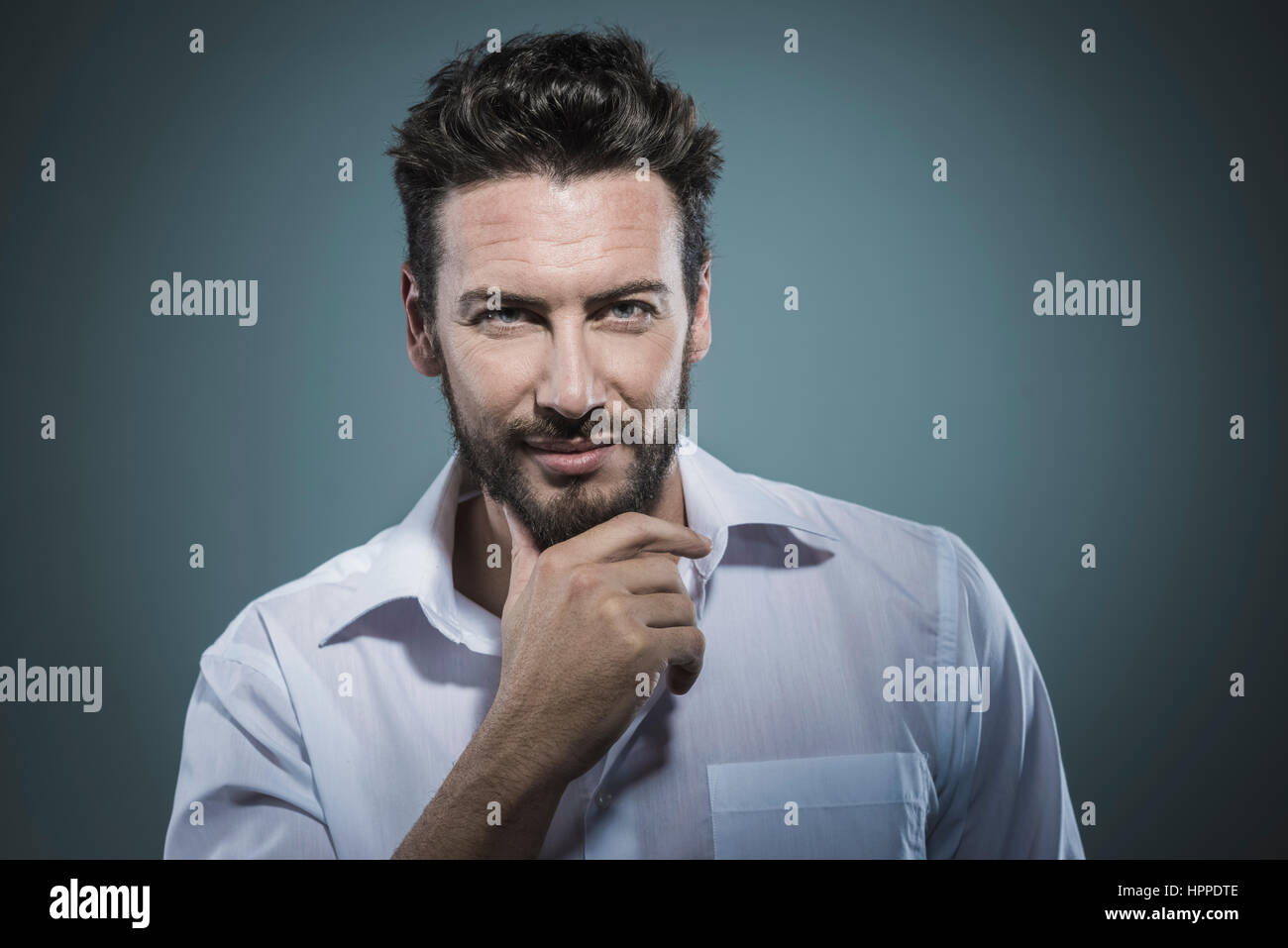 Handsome smiling man with hand on chin posing Banque D'Images Handsome smiling man with hand on chin posing Banque D'Images