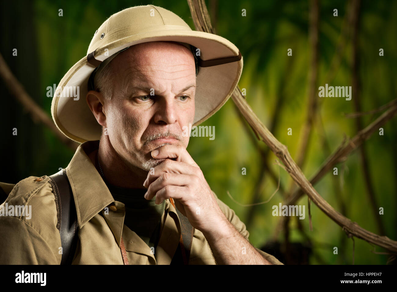 Aventurier dans la jungle rétro thinking with hand on chin. Banque D'Images Aventurier dans la jungle rétro thinking with hand on chin. Banque D'Images