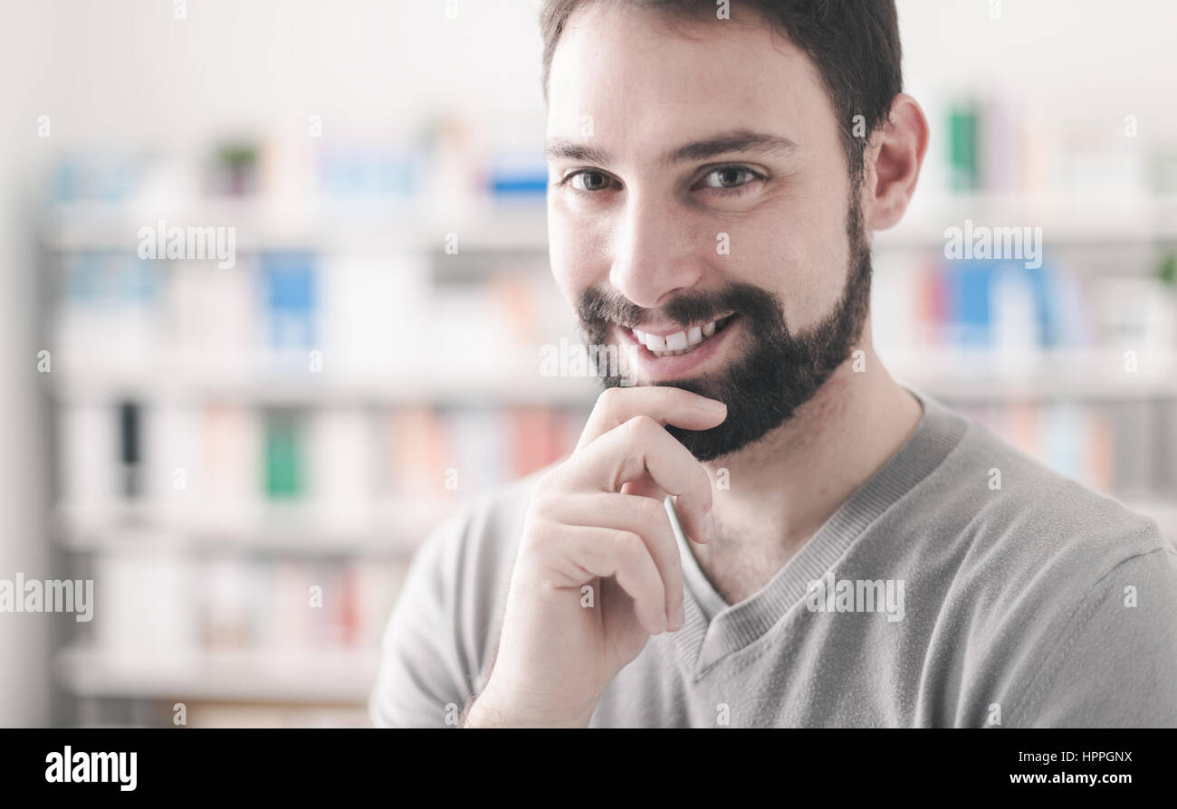 Confiant thoughtful handsome man posing with hand on chin, il est smiling at camera Banque D'Images Confiant thoughtful handsome man posing with hand on chin, il est smiling at camera Banque D'Images