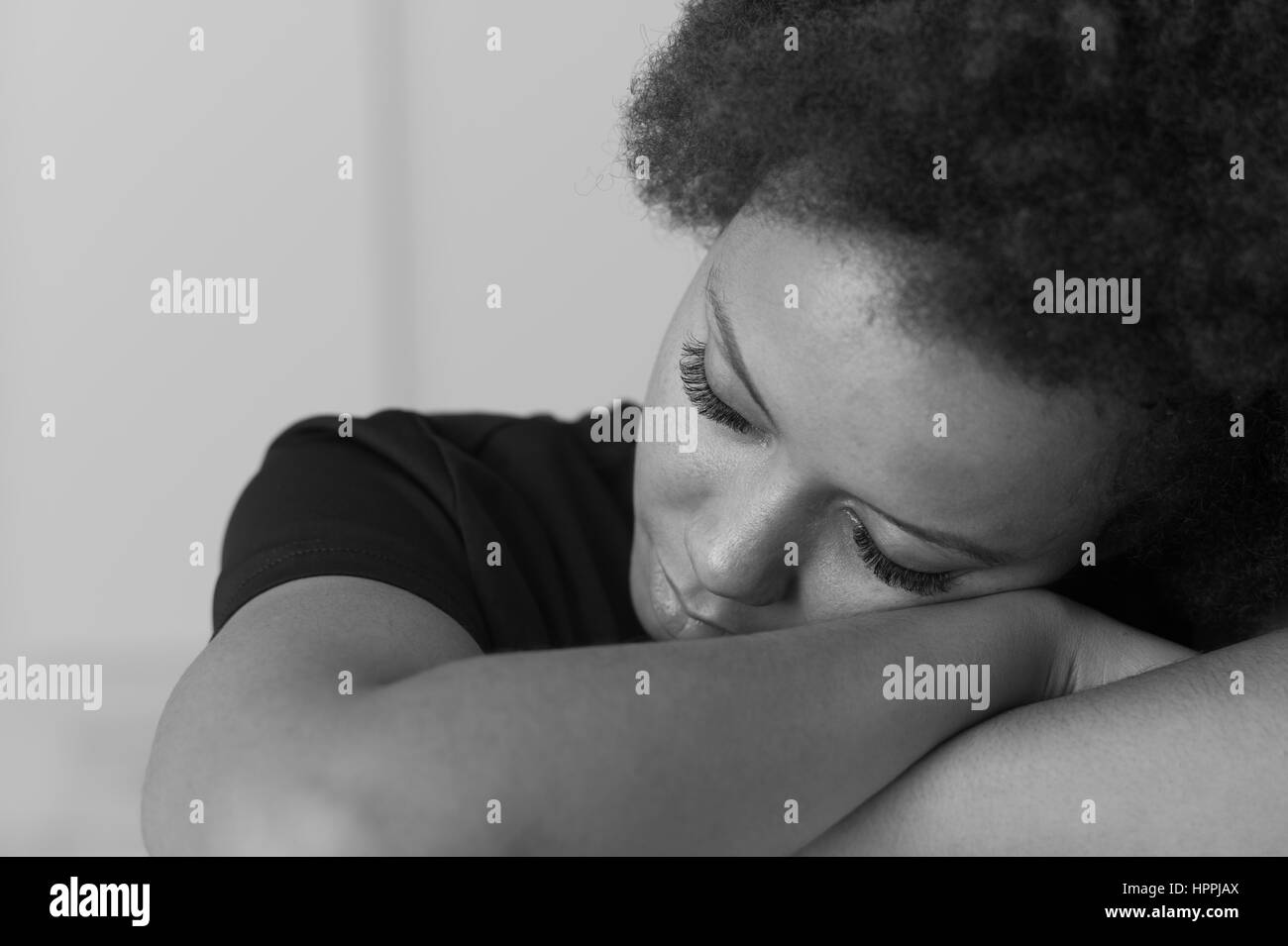 Young african american woman relaxing et appuyée sur son bras avec les yeux fermés Banque D'Images