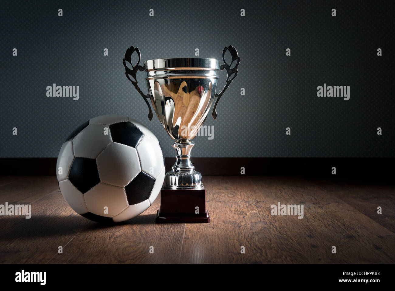 Trophée de la coupe d'or et ballon de soccer sur plancher de bois franc, concept gagnant. Banque D'Images