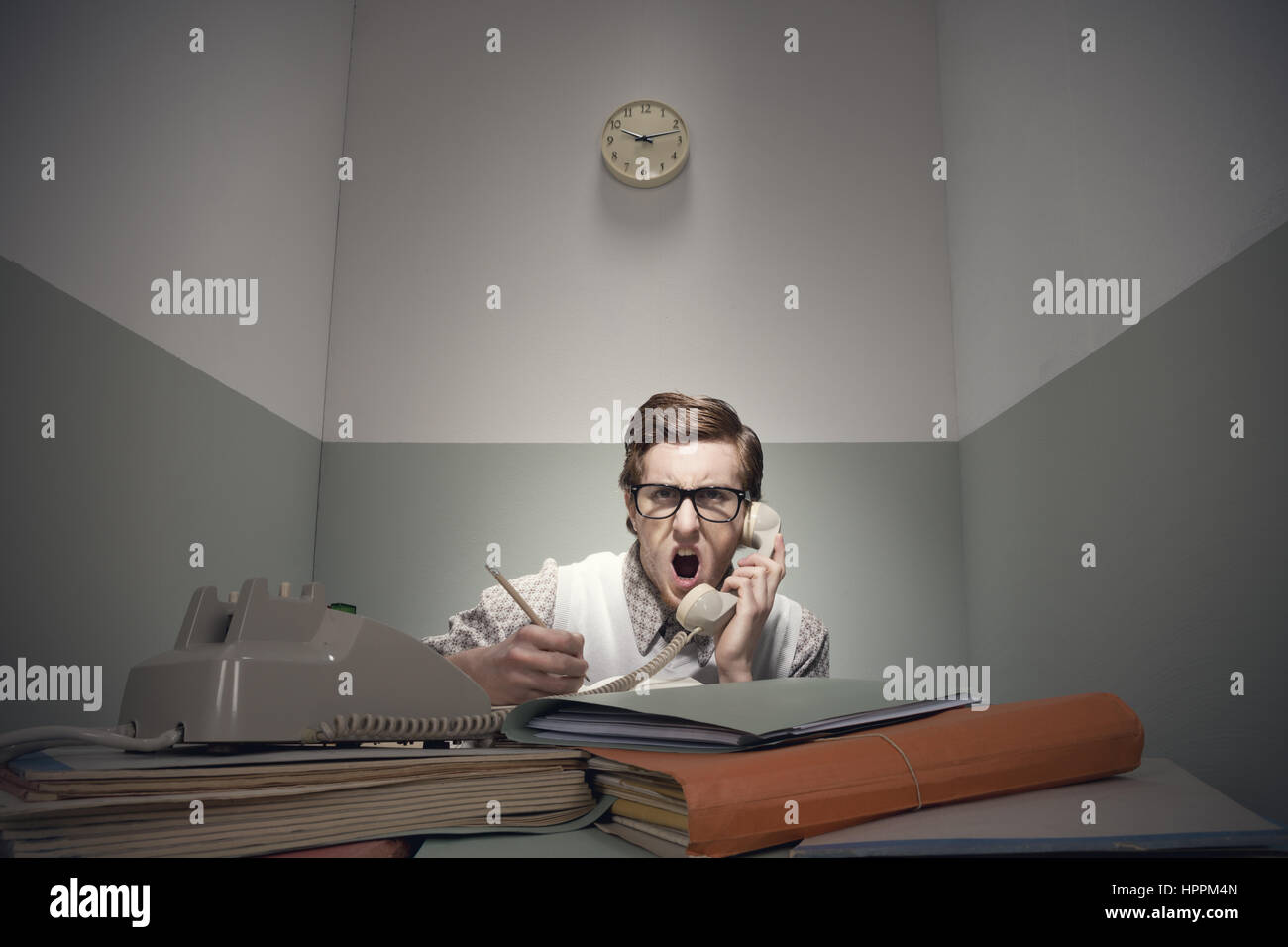 Angry nerd guy au téléphone avec bureau malpropre. Banque D'Images
