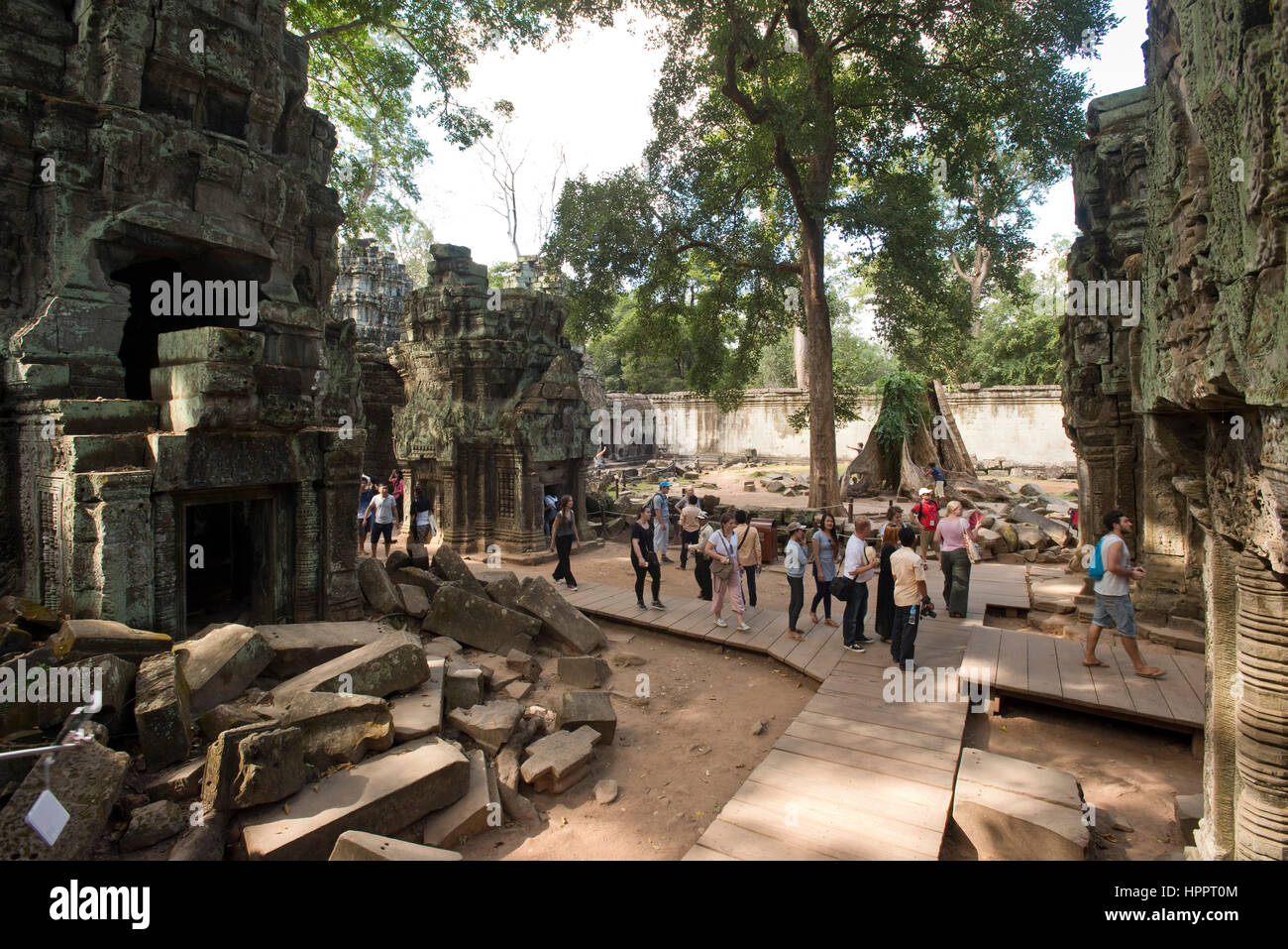 Une vue grand angle de touristes passant dans le complexe du temple Ta Prohm, Angkor. Banque D'Images