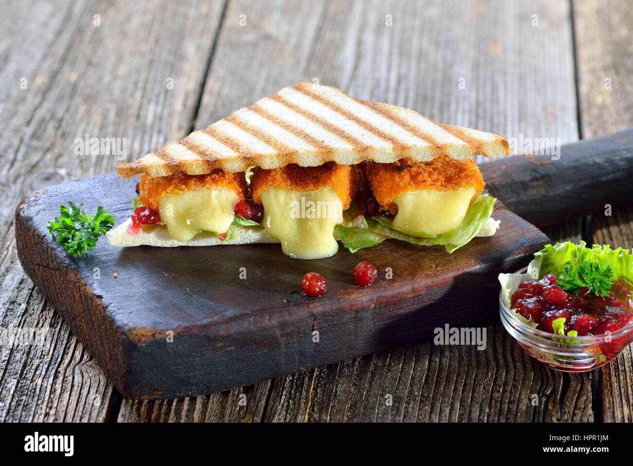 Panini grillé triangles avec fromage camembert pané mini pains, de canneberges et de laitue iceberg servi sur une planche à découper en bois Banque D'Images