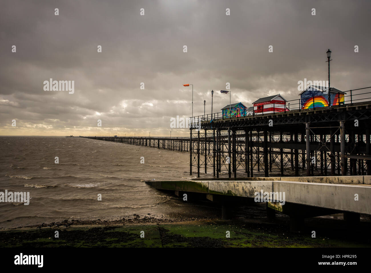 Southend Pier pendant la tempête Doris, avec de lourds nuages rendant les cabanes multicolores en évidence. Mauvais temps sur l'estuaire de la Tamise Banque D'Images