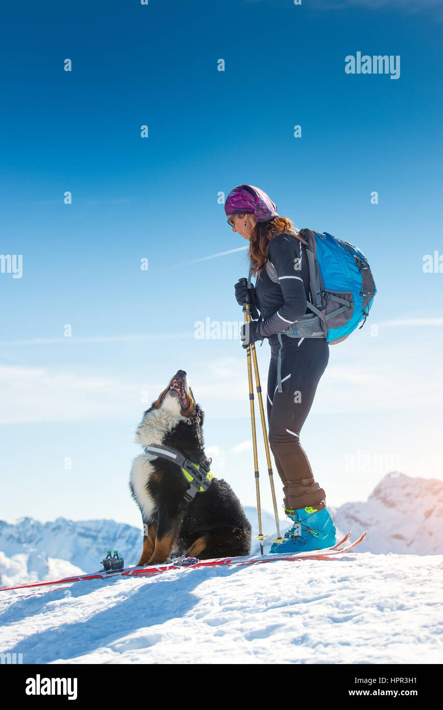 Fille au sommet d'une montagne en hiver avec le ski et son ami chien bouvier bernois Banque D'Images