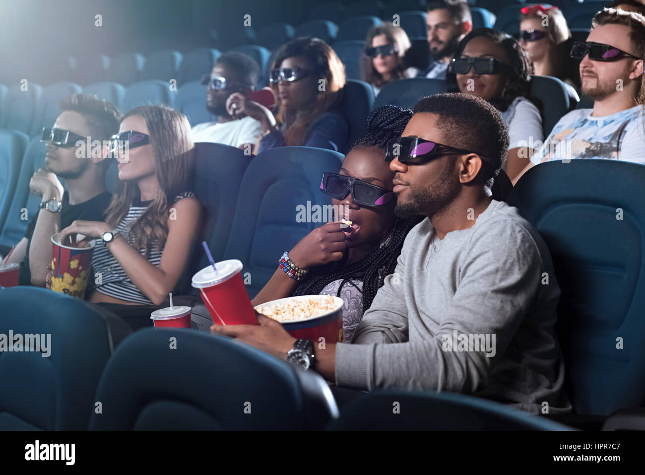 Snack-classique. Portrait of a young woman eating popcorn tout en regardant un film avec son petit ami spectateurs portant des lunettes 3D Banque D'Images