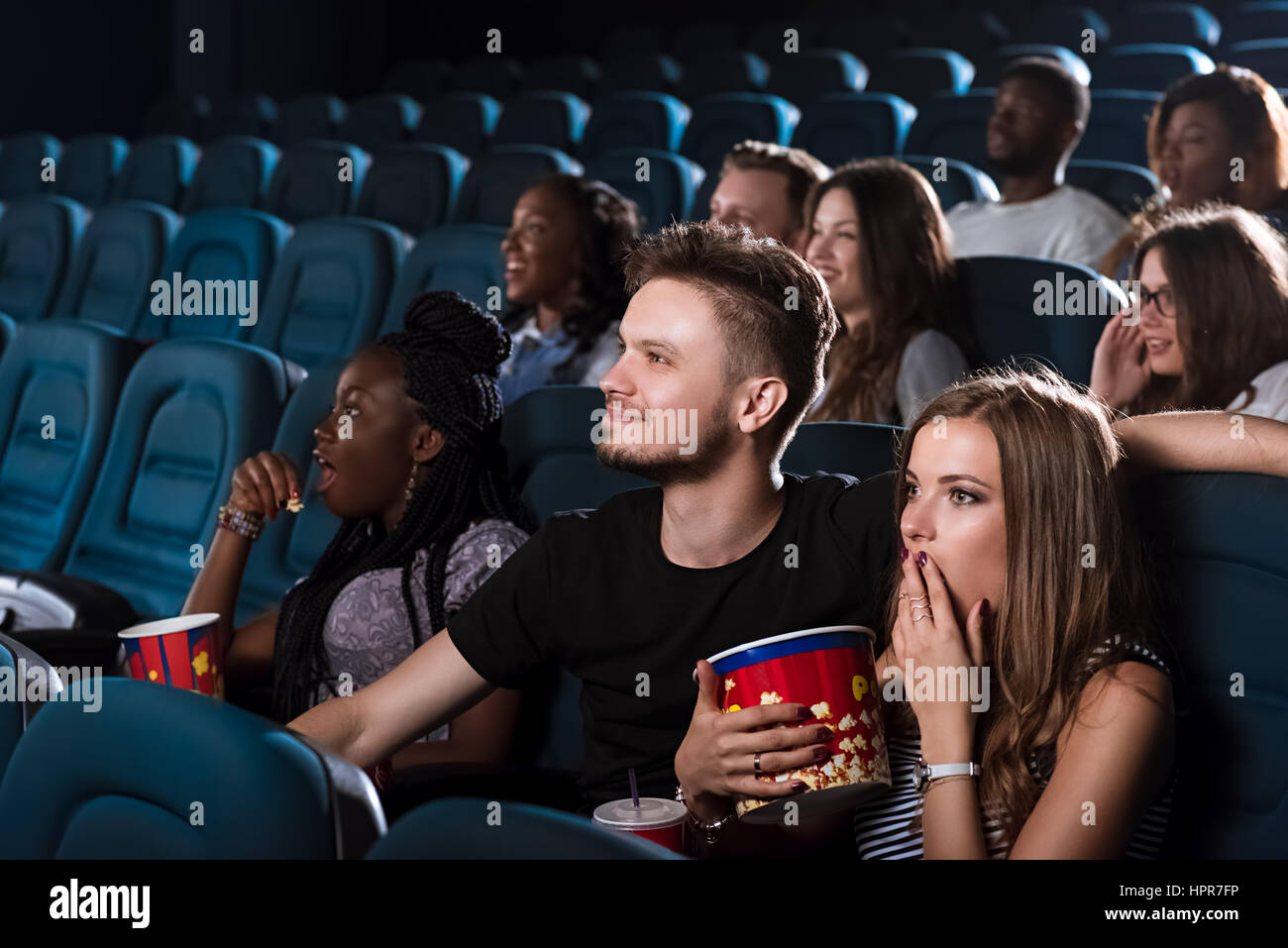 Date d'émotionnel. Belle jeune femme à la recherche a choqué tout en regardant un film avec son petit ami au cinéma Banque D'Images