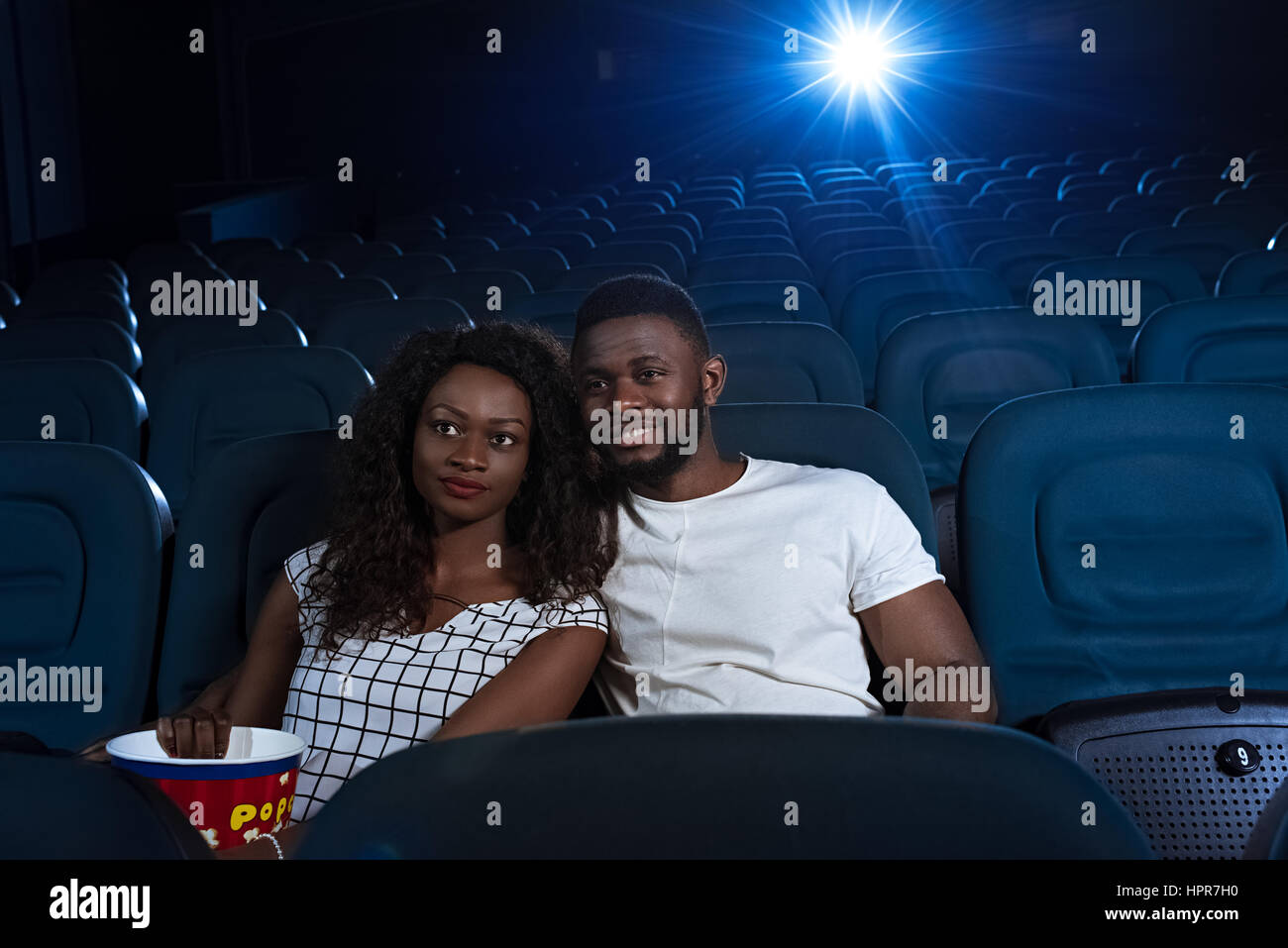 Date de détente. Jeunes et belles à regarder un film African couple hugging at le cinéma local Banque D'Images