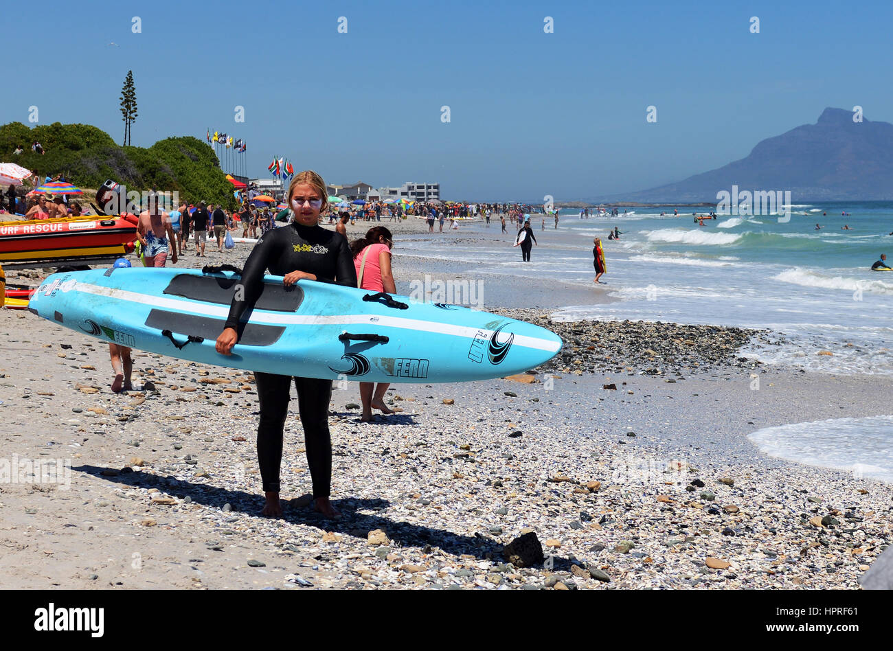 Une jeune femme sud-africaine tenant son paddle board sur la plage de Bloubergstrand près du Cap. Banque D'Images