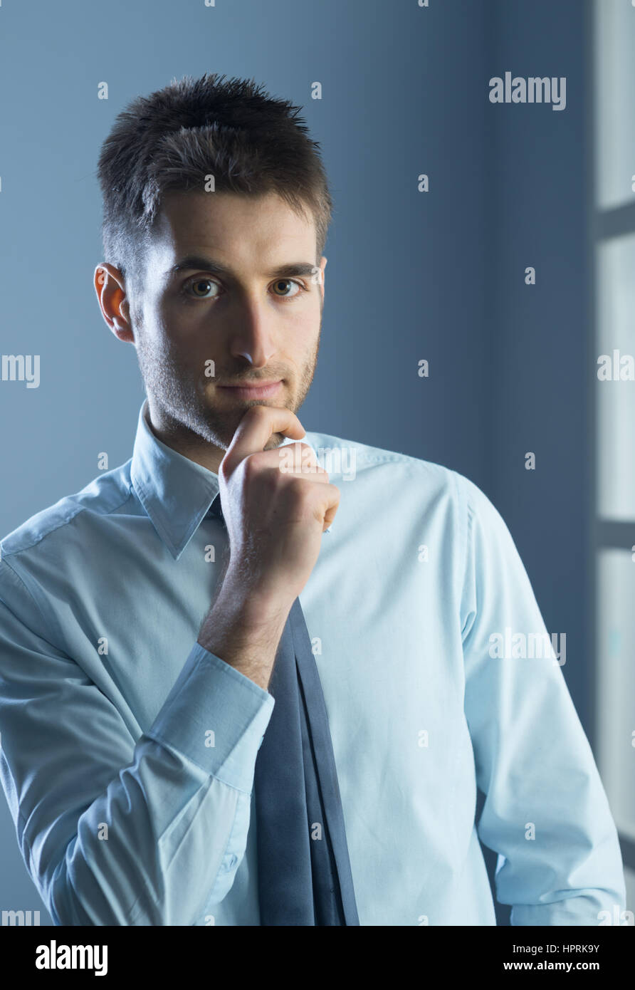 Young businessman with hand on chin, looking at camera. Banque D'Images Young businessman with hand on chin, looking at camera. Banque D'Images
