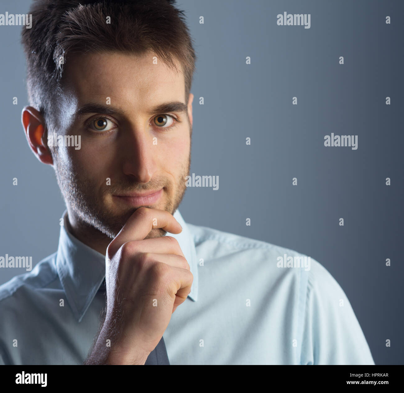Young businessman with hand on chin, looking at camera. Banque D'Images Young businessman with hand on chin, looking at camera. Banque D'Images