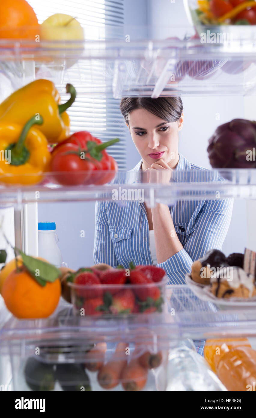 Femme à la recherche de délicieuses pâtisseries avec la main sur le menton. Banque D'Images Femme à la recherche de délicieuses pâtisseries avec la main sur le menton. Banque D'Images