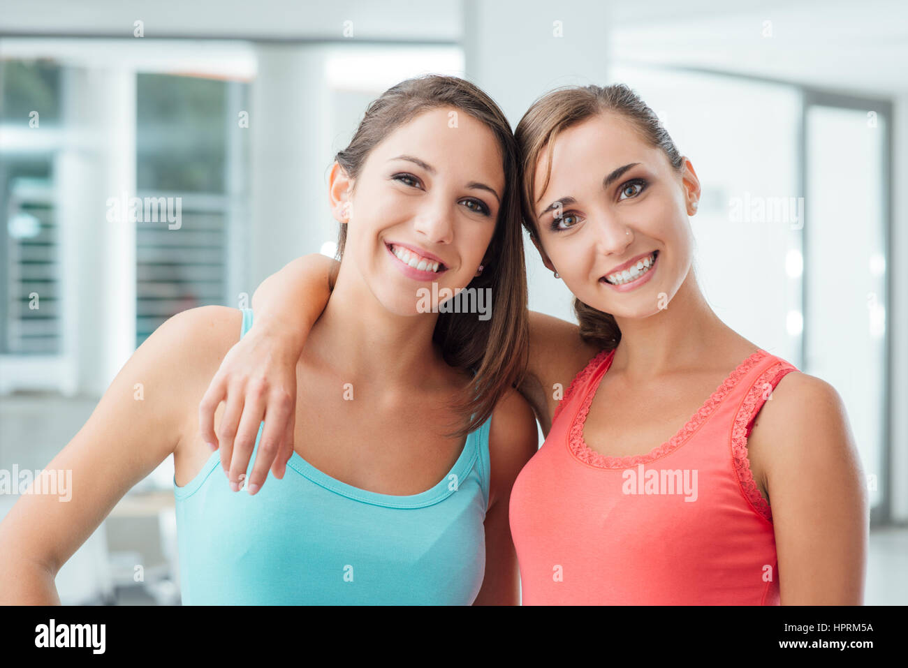 Cute smiling girls posing together and looking at camera, l'un est hugging her friend Banque D'Images