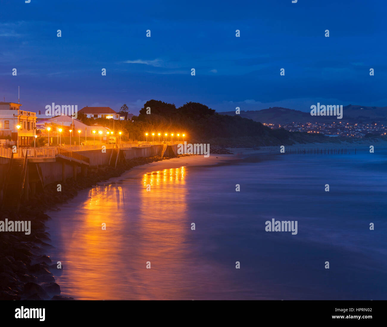 Dunedin, Otago, Nouvelle-Zélande. Afficher le long de l'esplanade illuminée au crépuscule, St Clair, lumières reflétées dans l'océan Pacifique. Banque D'Images