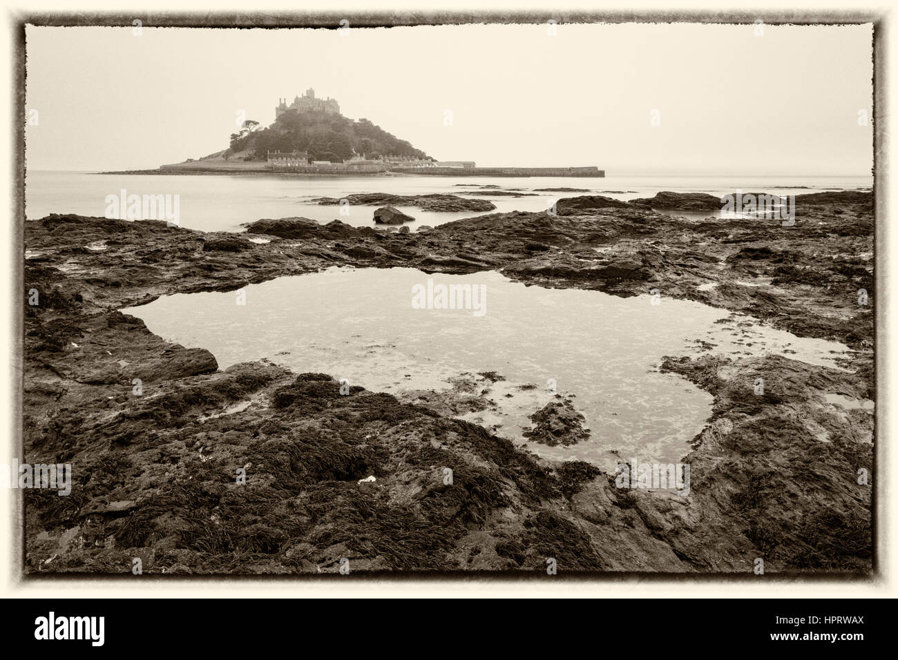 Aube tonique tourné sur matin brumeux avec une longue exposition de St Michael's Mount avec piscine dans les rochers en premier plan, West Cornwall, England, UK en février Banque D'Images