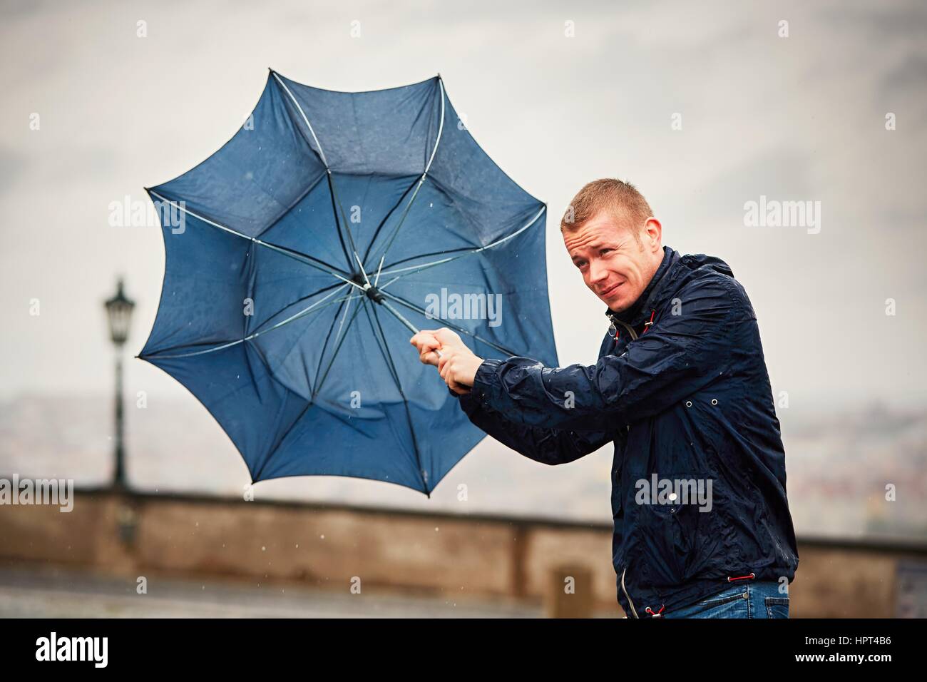 La pluie dans la ville. Jeune homme est tenue bleu lors d'orage. Rue de Prague, République tchèque. Banque D'Images