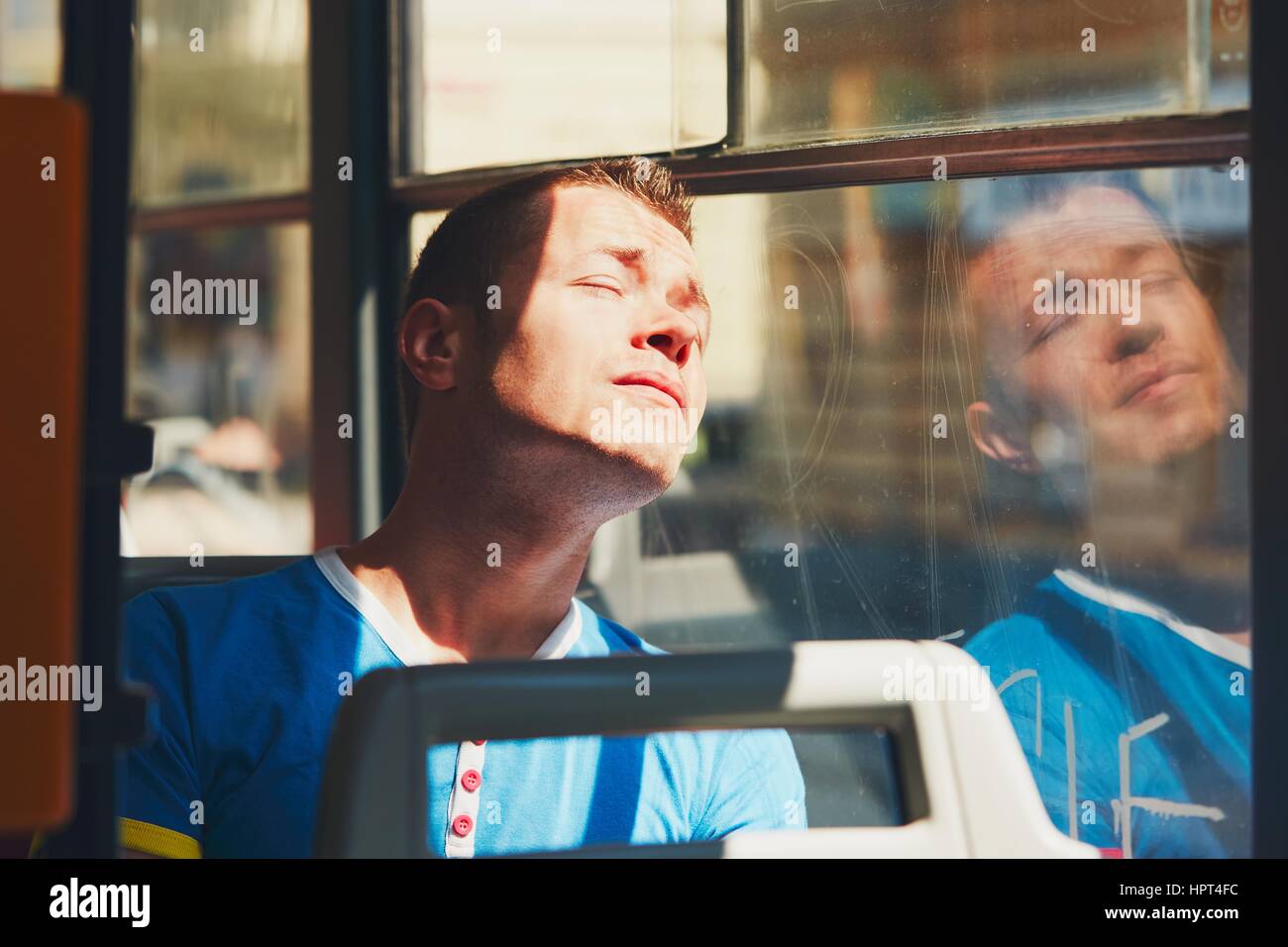 La vie quotidienne et se rendre au travail en transports publics. Beau jeune homme se déplace en tram (bus). Homme fatigué en journée chaude. Prague, République Tchèque Banque D'Images