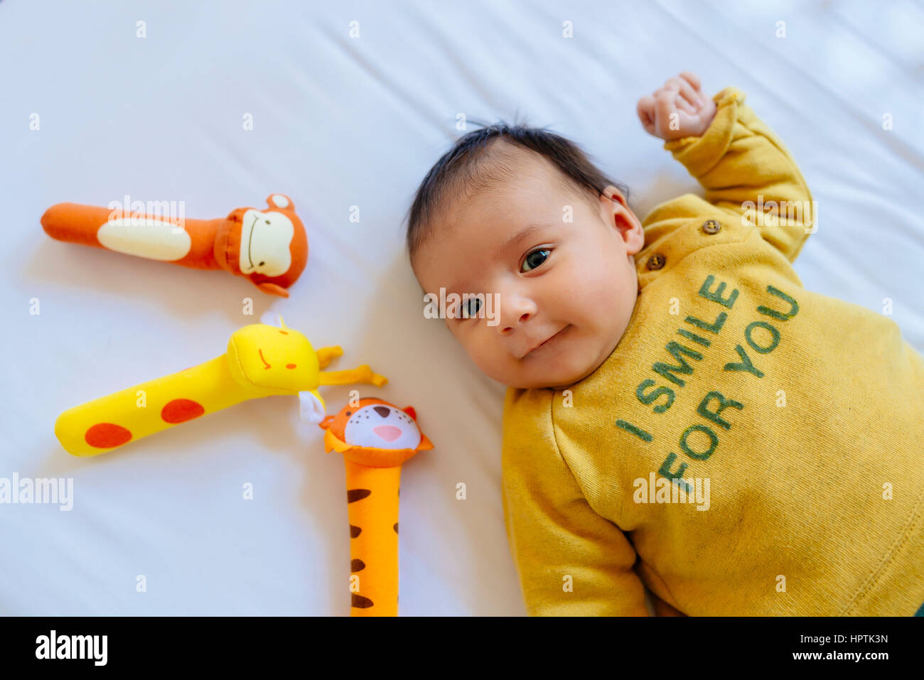 Baby Girl avec des jouets sur le lit Banque D'Images